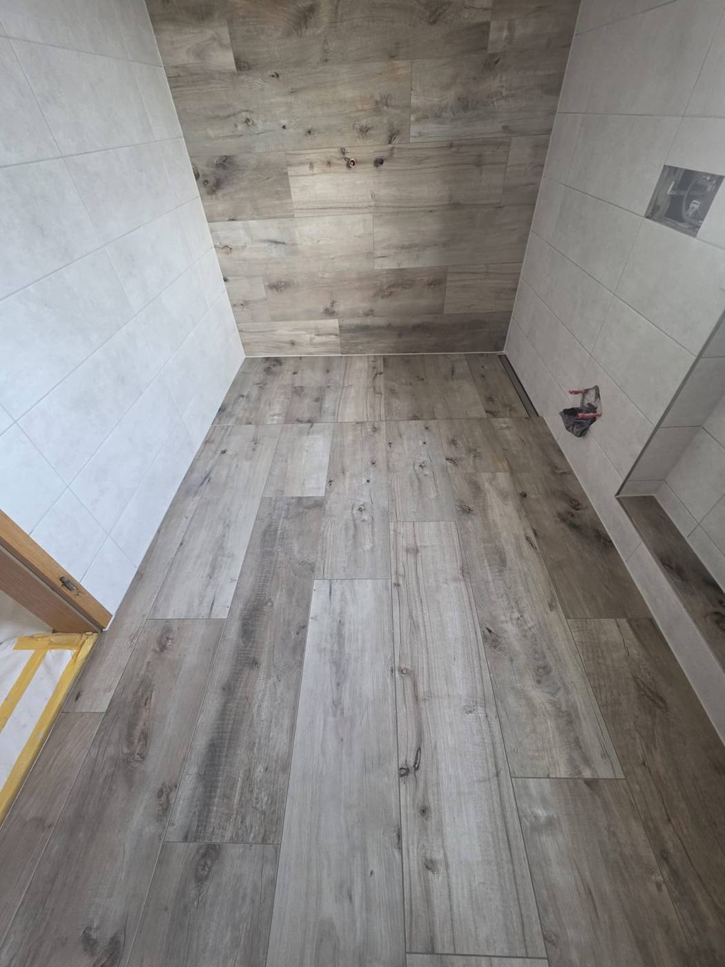 Bad mit Fliesen in Holzoptik an Boden und Rückwand